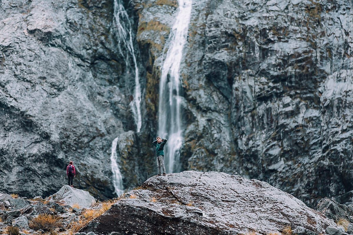 An athletic couple climbs to the basin of a waterfall