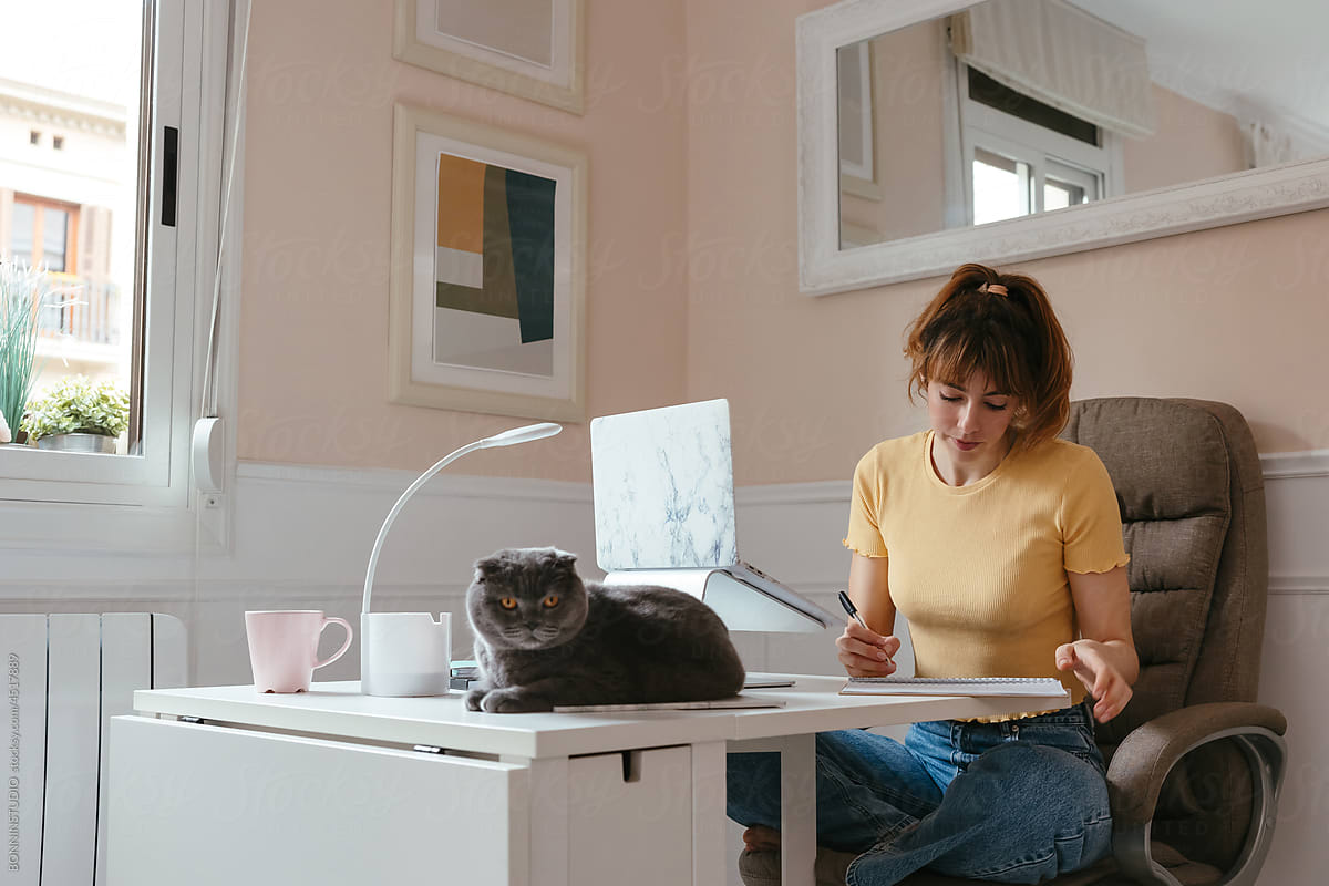 Woman making notes near cat