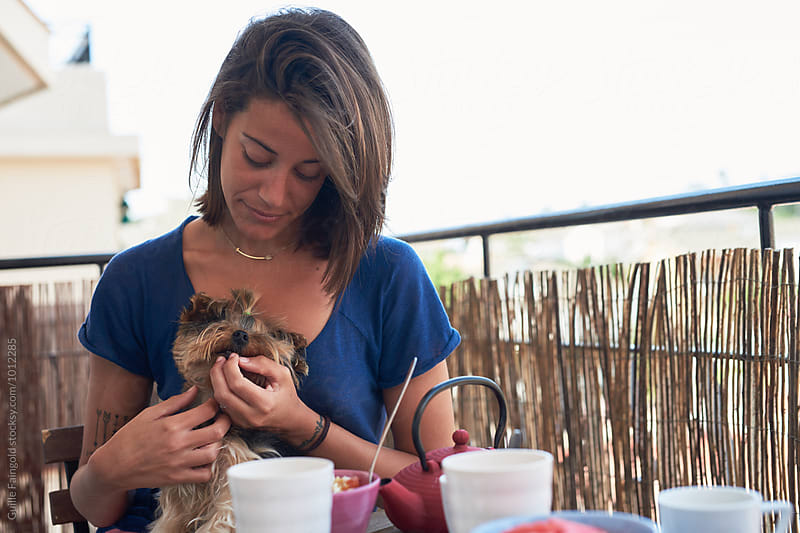 Young brunette hugging with her pet dog at table outdoor
