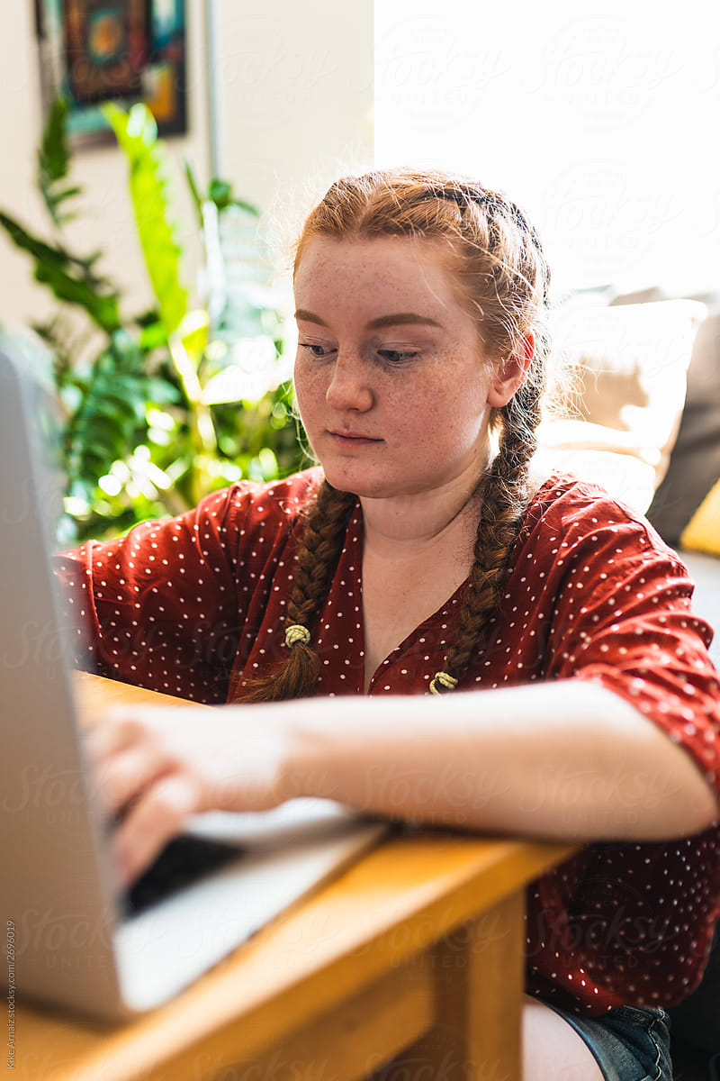 Young red-haired woman using laptop. indoors in an apartment