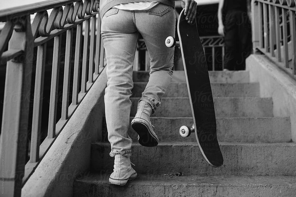 Young woman walking up concrete stairs with a skateboard