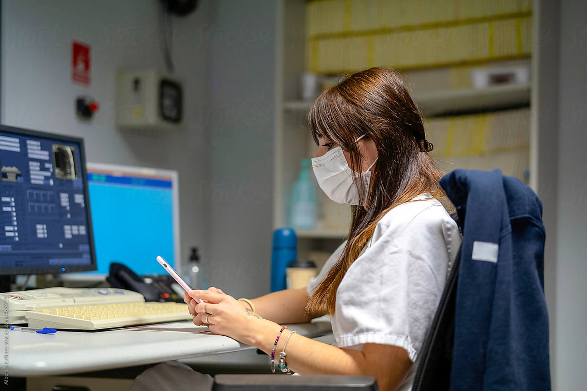 Nurse consulting her cell phone on the work table