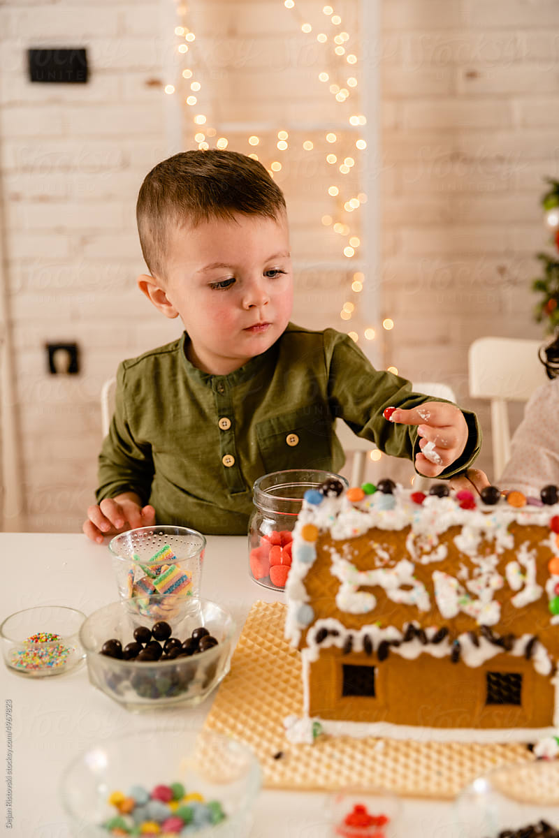 Boy eating candys while decorating  Gingerbread house at home