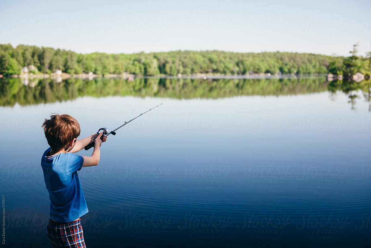 Boy casts his fishing pole into a lake