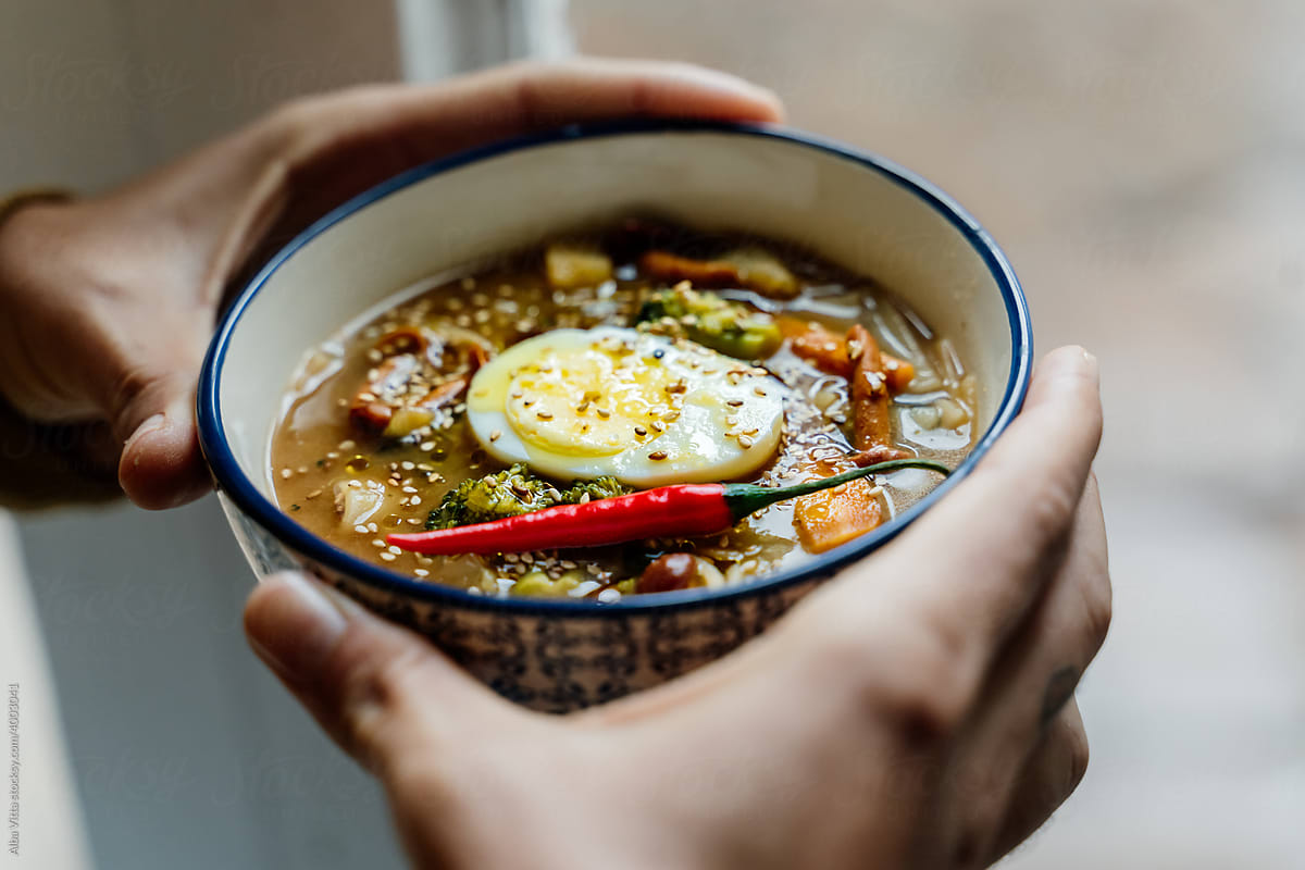 Man holding Bowl with noodles ramen and egg on counter