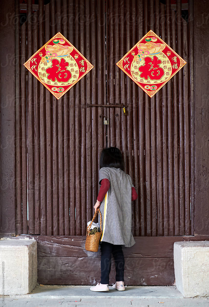 Cute Asian little girl in front of a traditional Chinese wooden door.