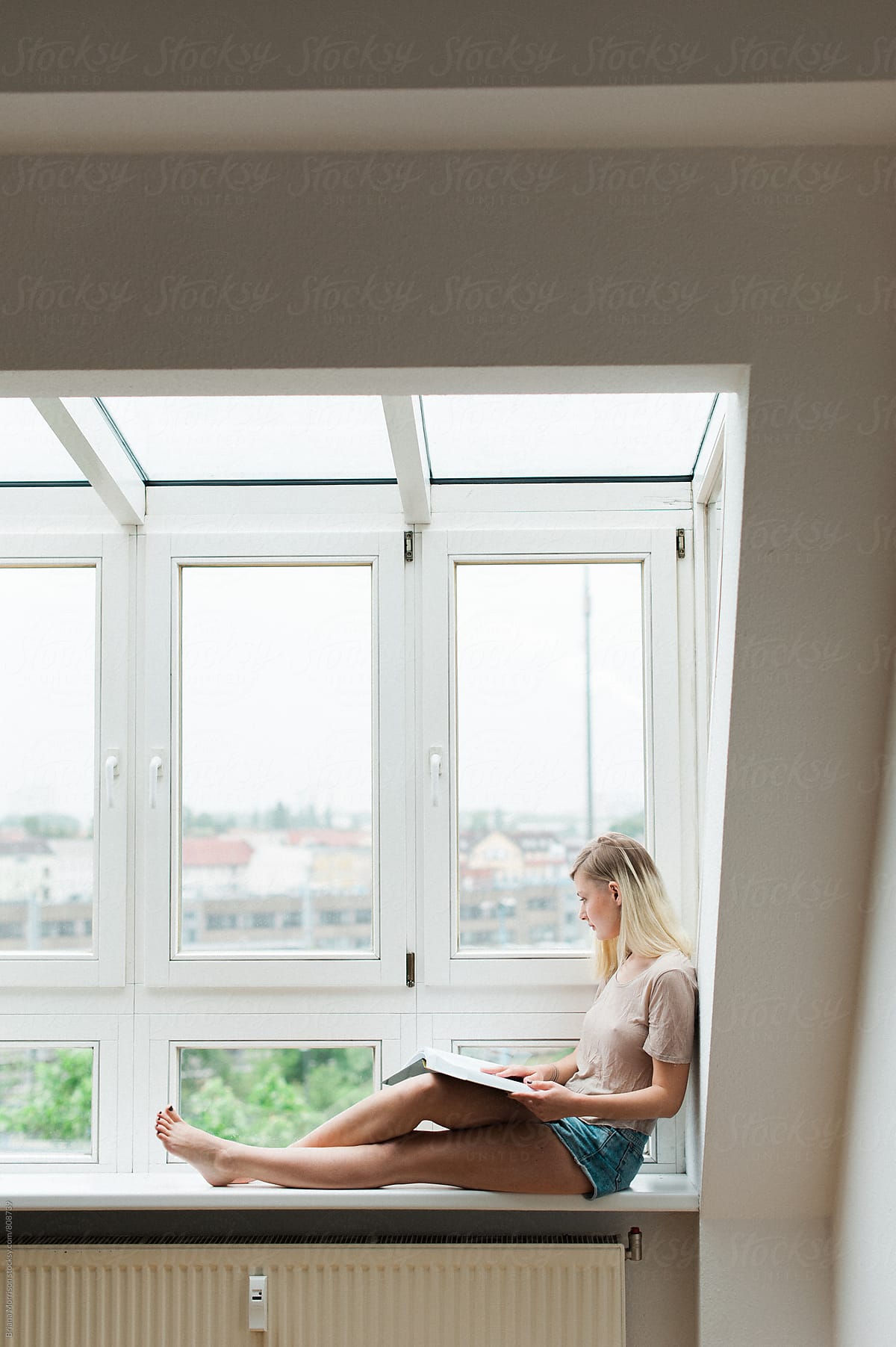 Woman Reading Sitting on a Window Ledge