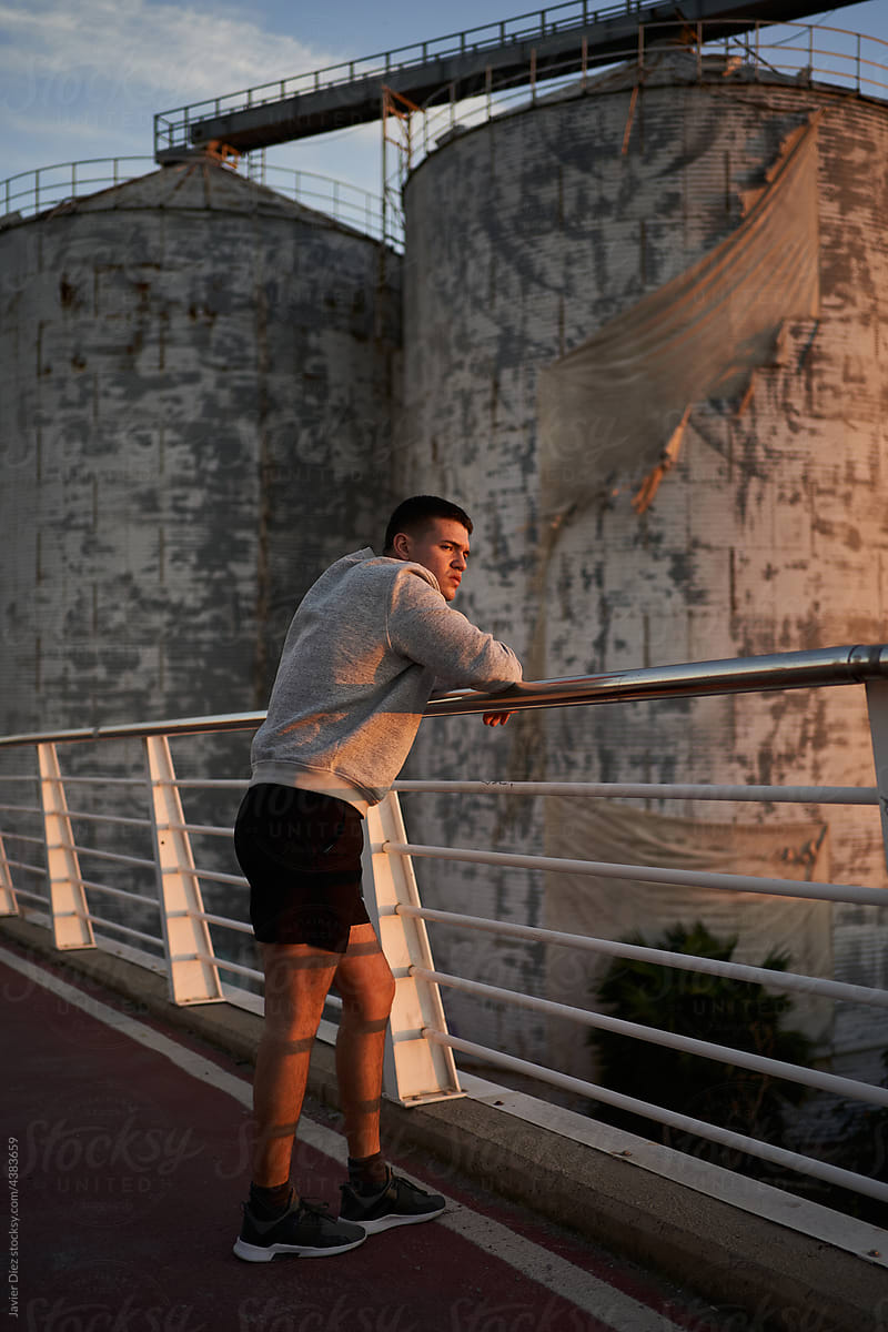 Self assured sportsman standing on bridge in sunset