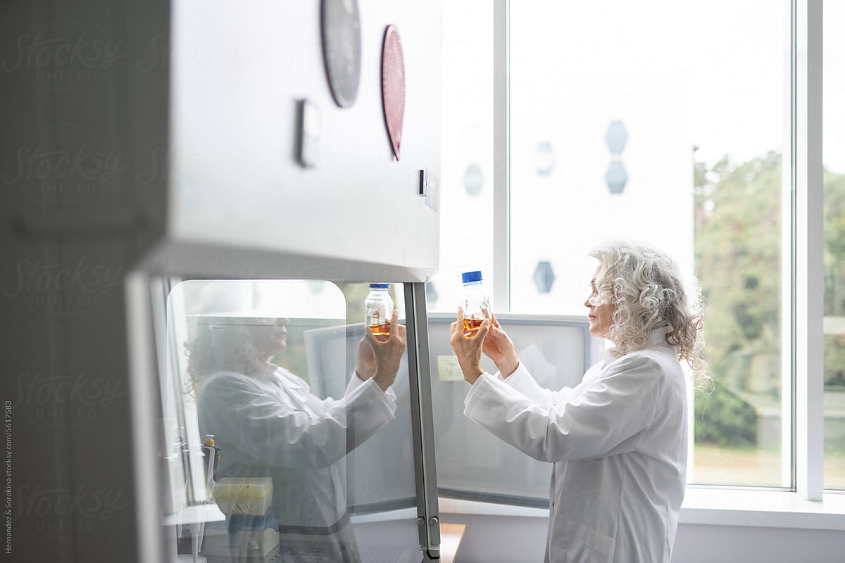 Senior Female Researcher Holding Bottle In Laboratory