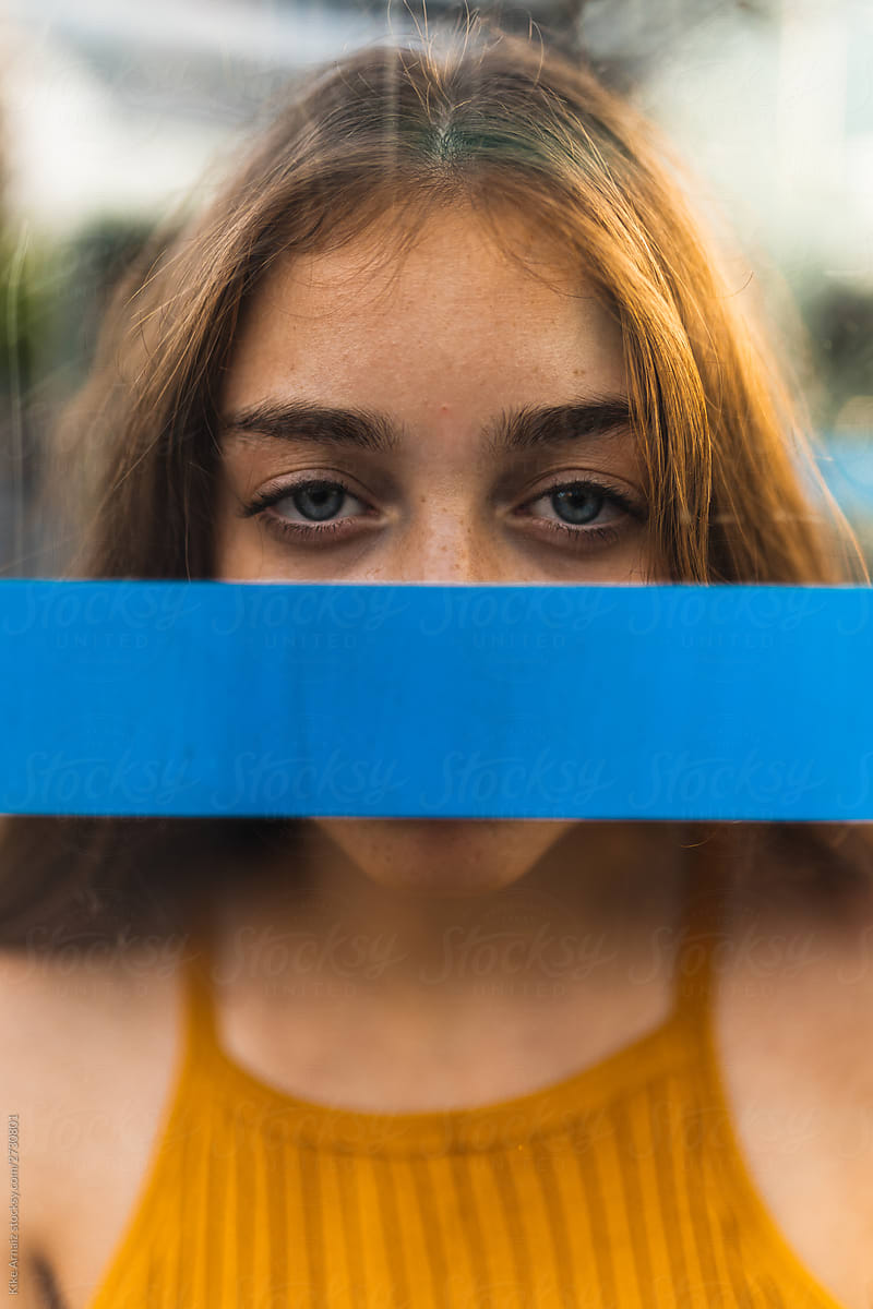 girl blue eyes behind a blue line covering her mouth