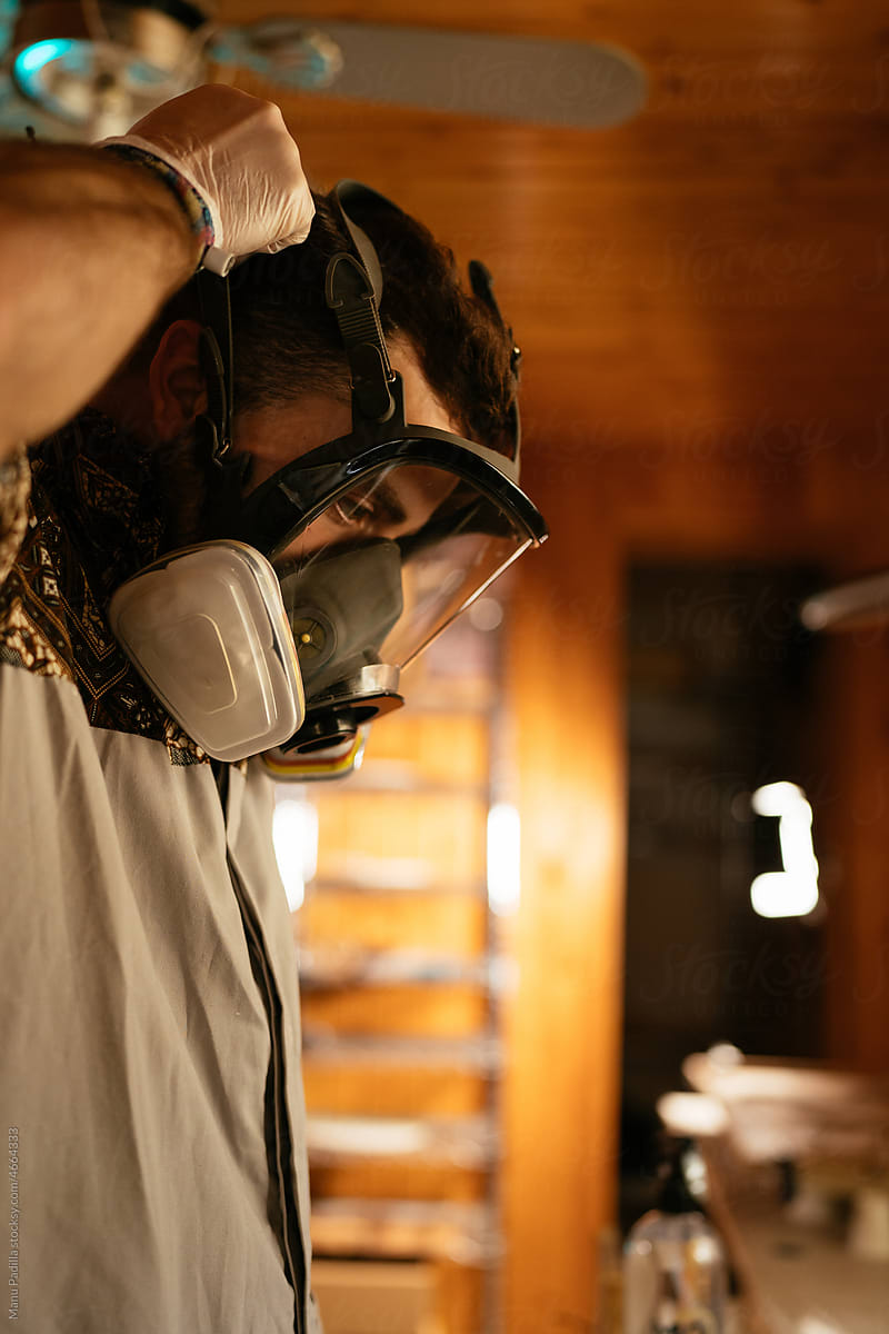 Young male master putting on respirator in workshop