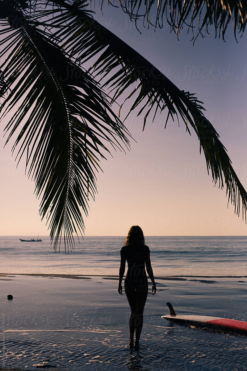 Woman walking along the beach at sunset