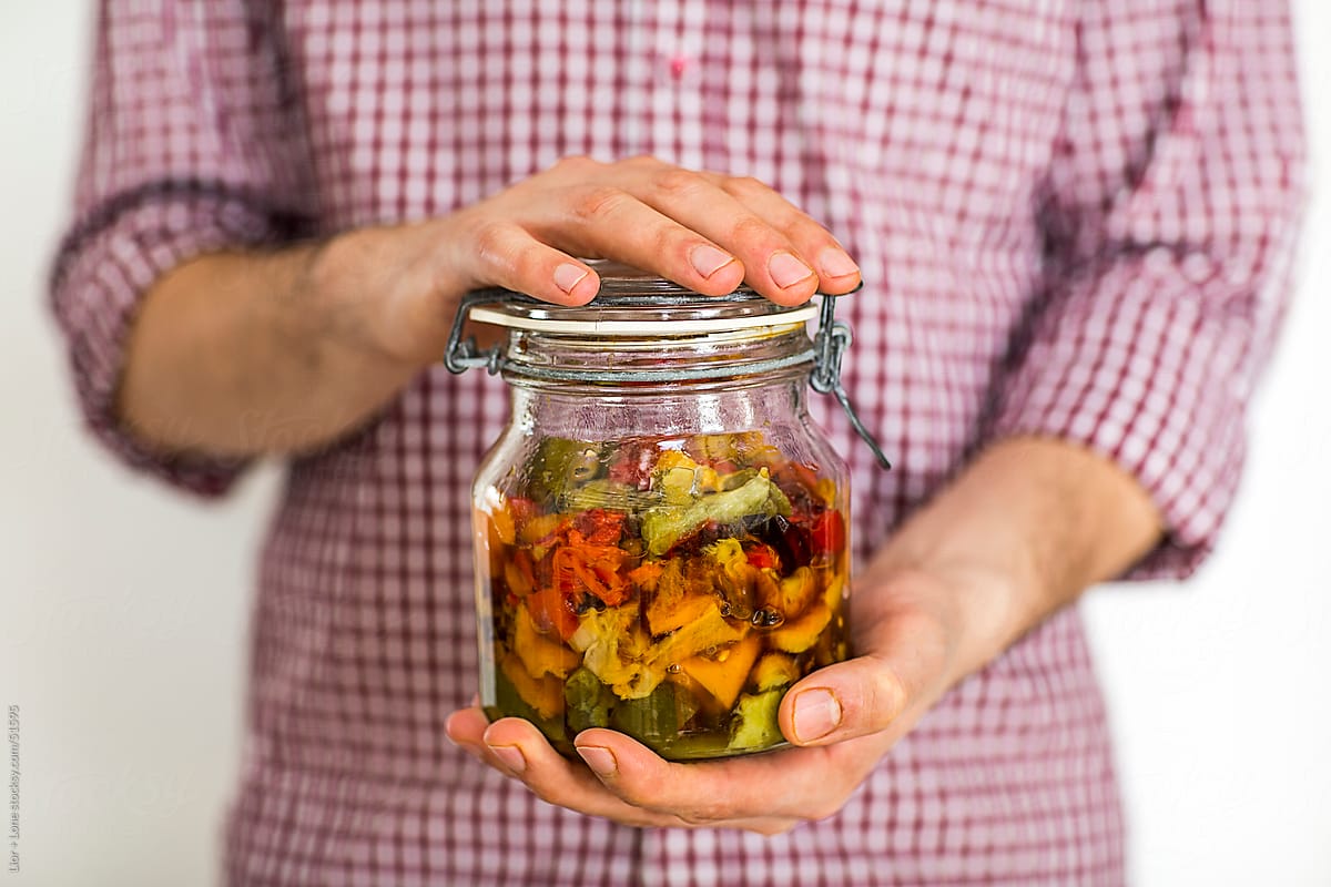 Manly hands holding a jar of pickled peppers