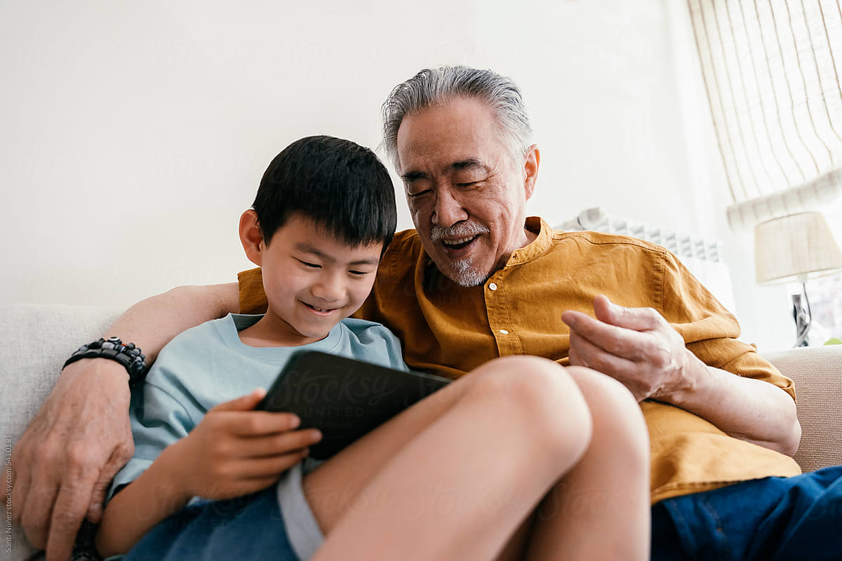 Chinese grandfather and grandson enjoy tablet\
 game.