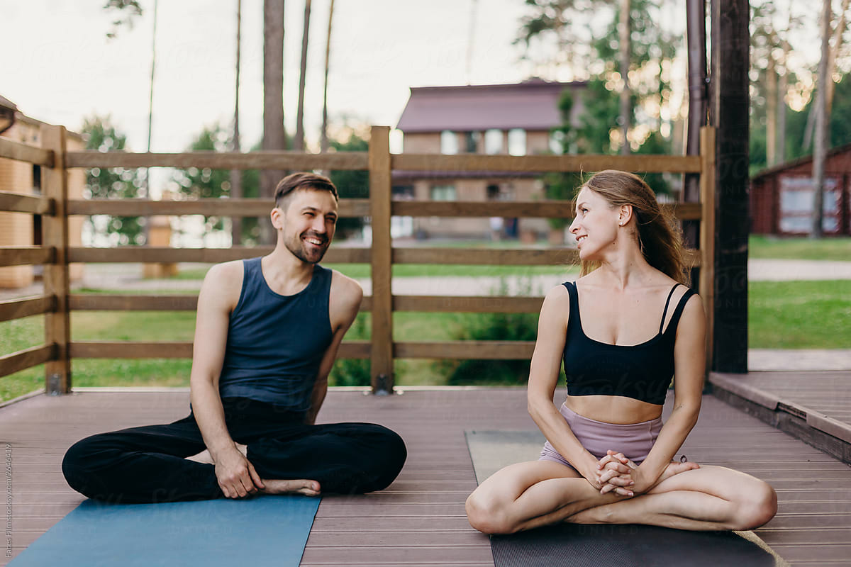 Happy yoga pair. Man and woman practice together outdoor and looking at aech other