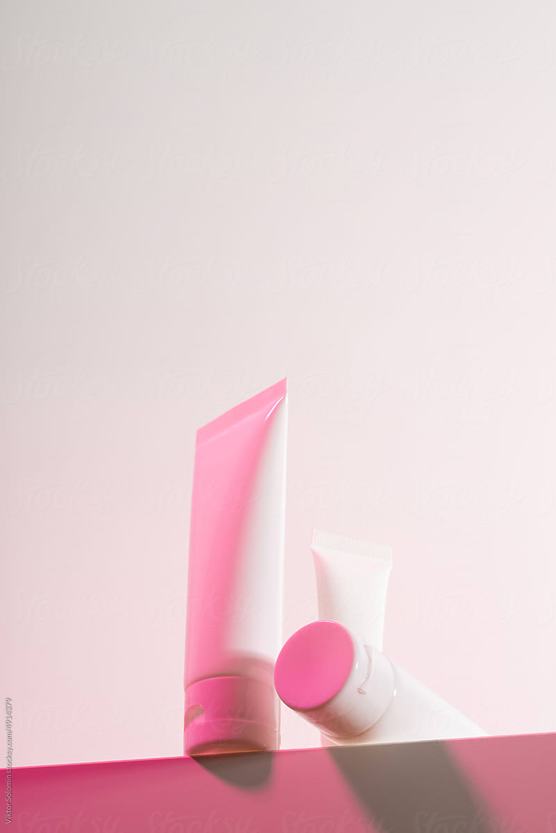 Set of pink hand-cream tubes on pink background in studio