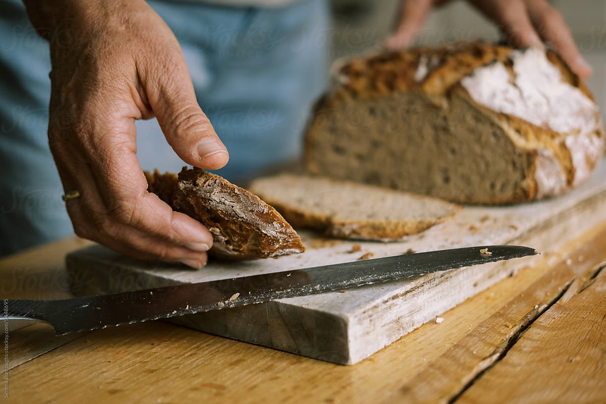 woman cutting fresh baked sourdough bread loaf