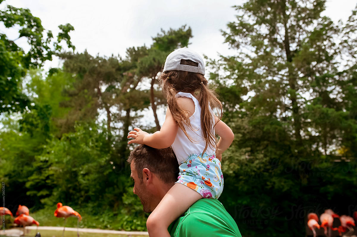 Daughter riding on dad\'s shoulders.