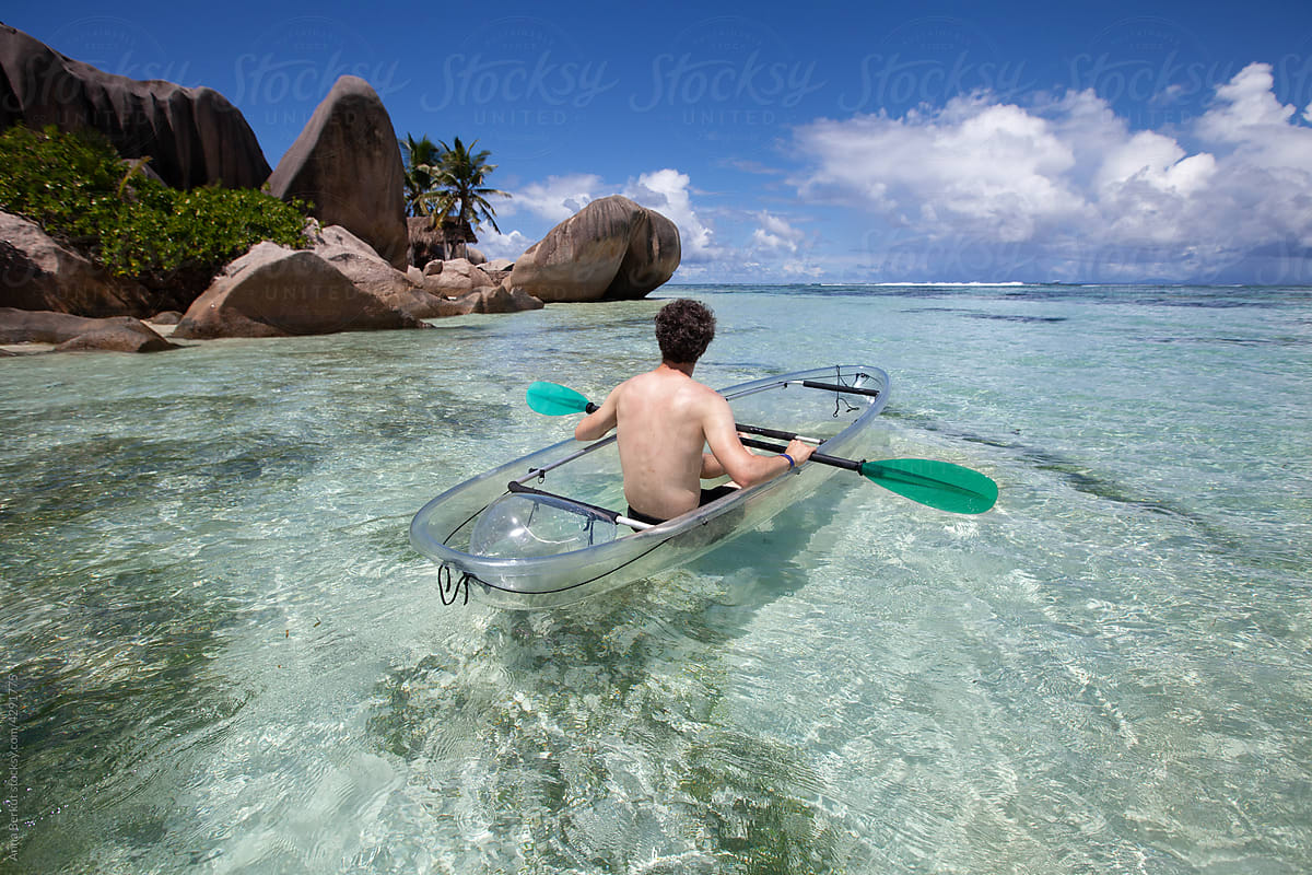 travel to paradise tropical beach, man on kayak, Seychelles, La Digue