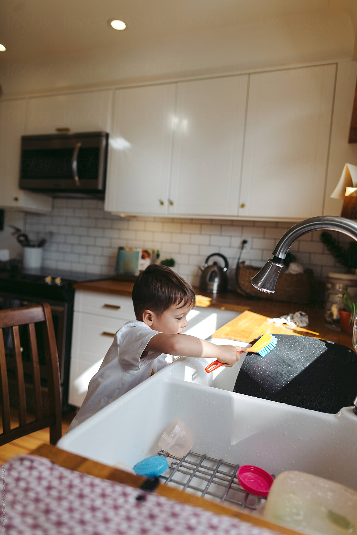 Happy little boy helping wash the dishes