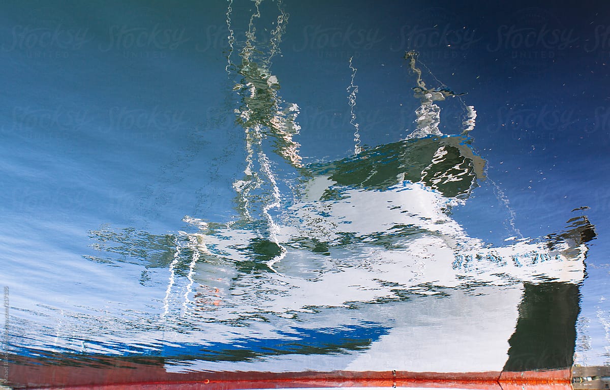 Flipped upside down reflection in water of a colorful boat in harbor
