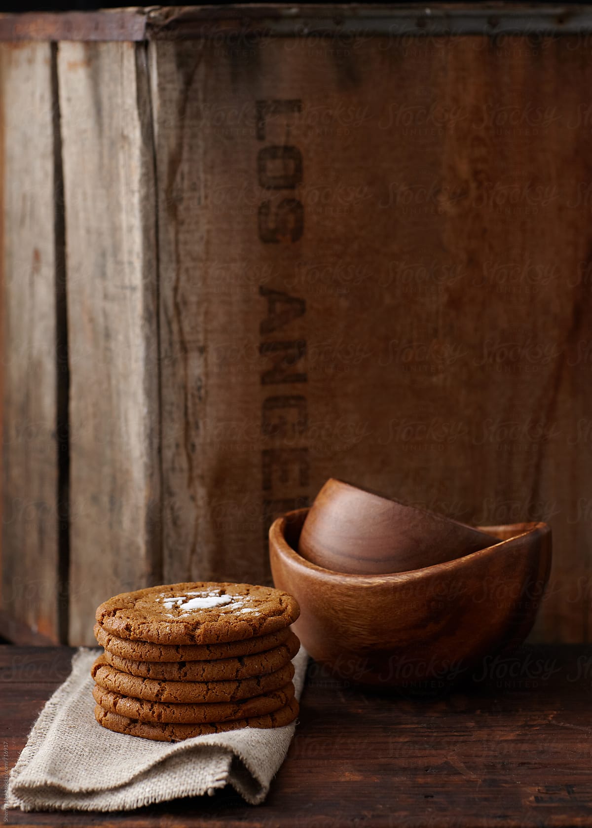 Stack of cookies and wood bowls in front of antique wood crate