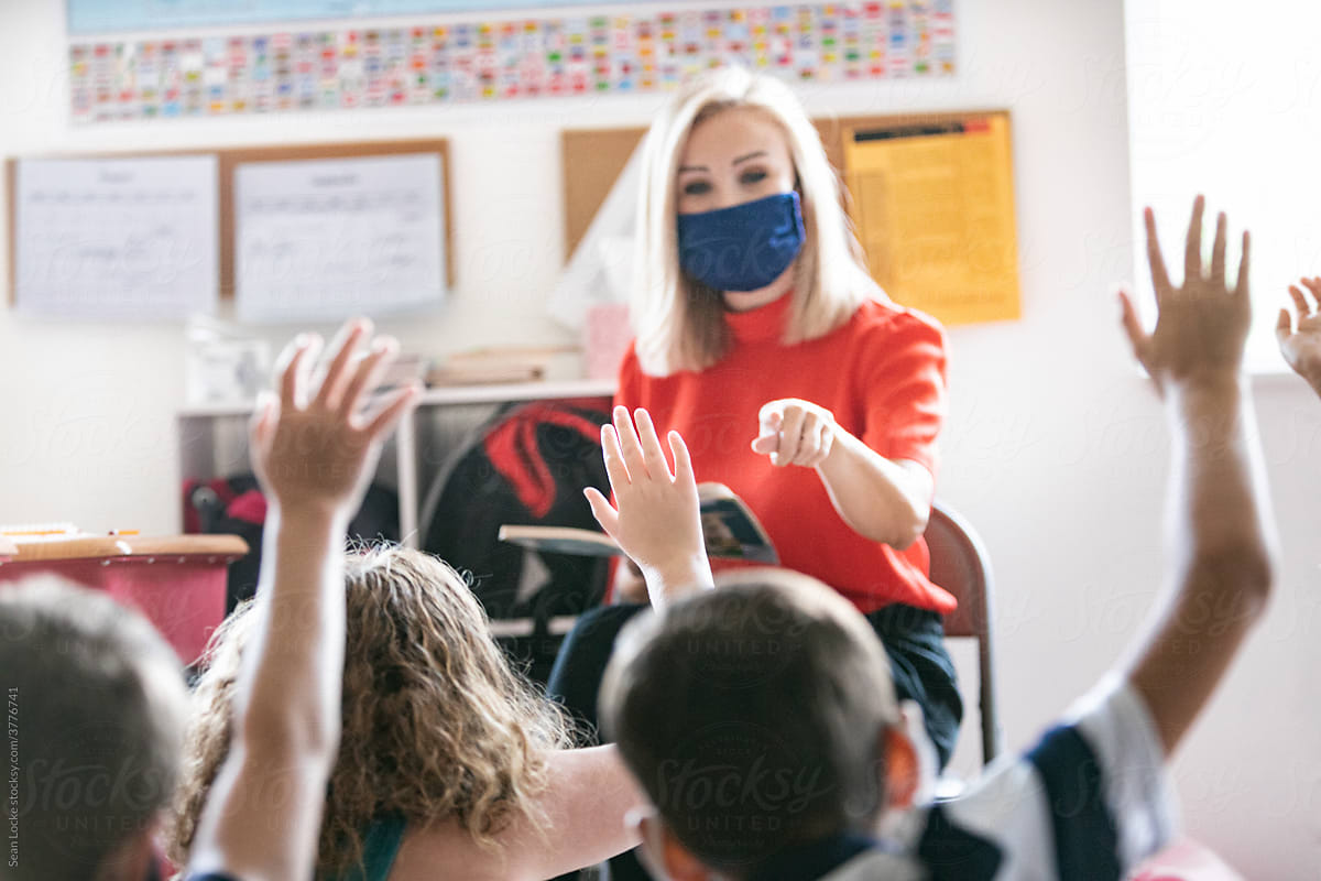 School: Teacher Wearing Face Mask And Reading Book Asks Question