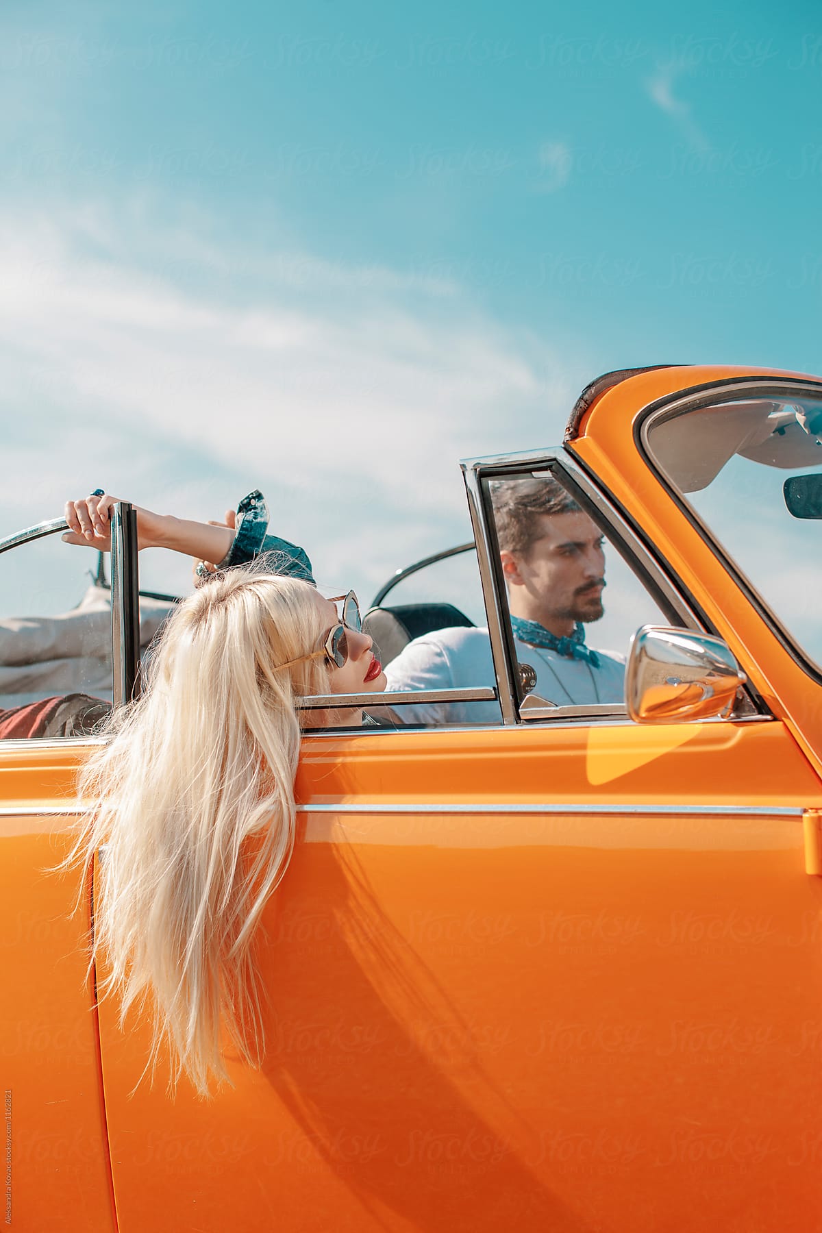 Attractive couple in a orange convertible car