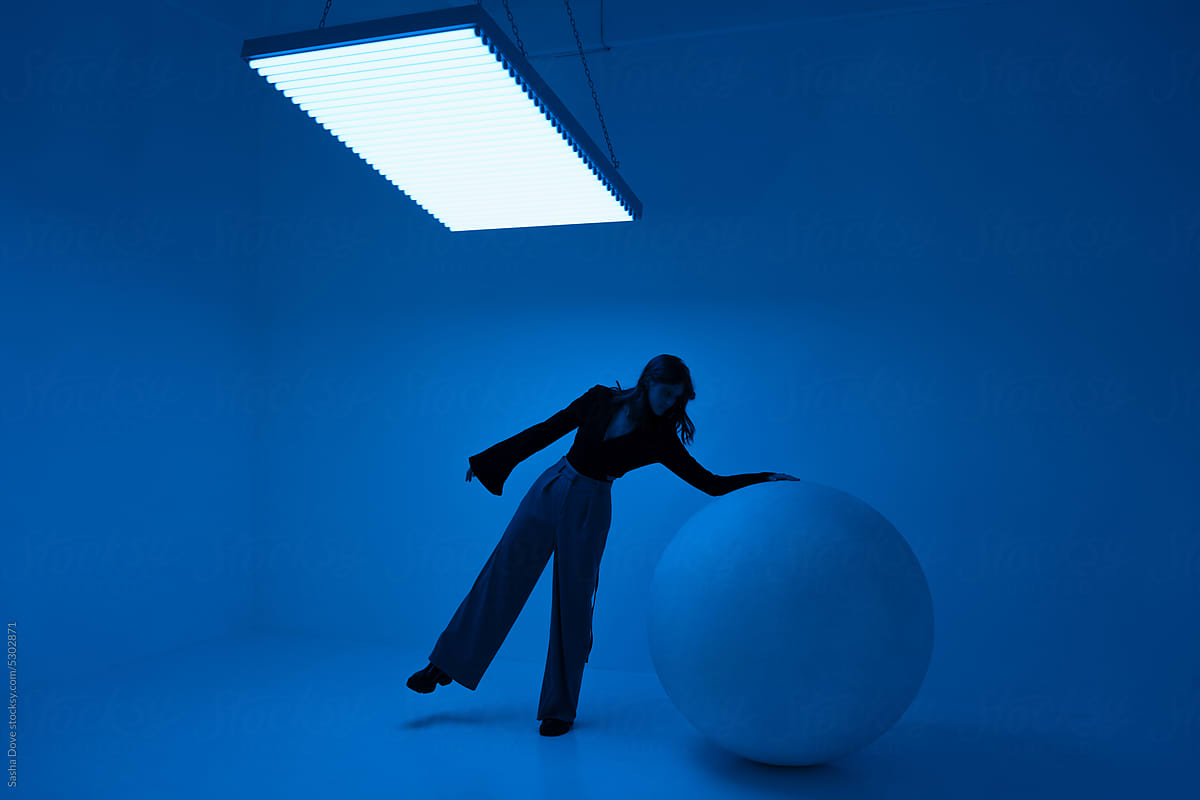 Young female standing in a room filled with blue light