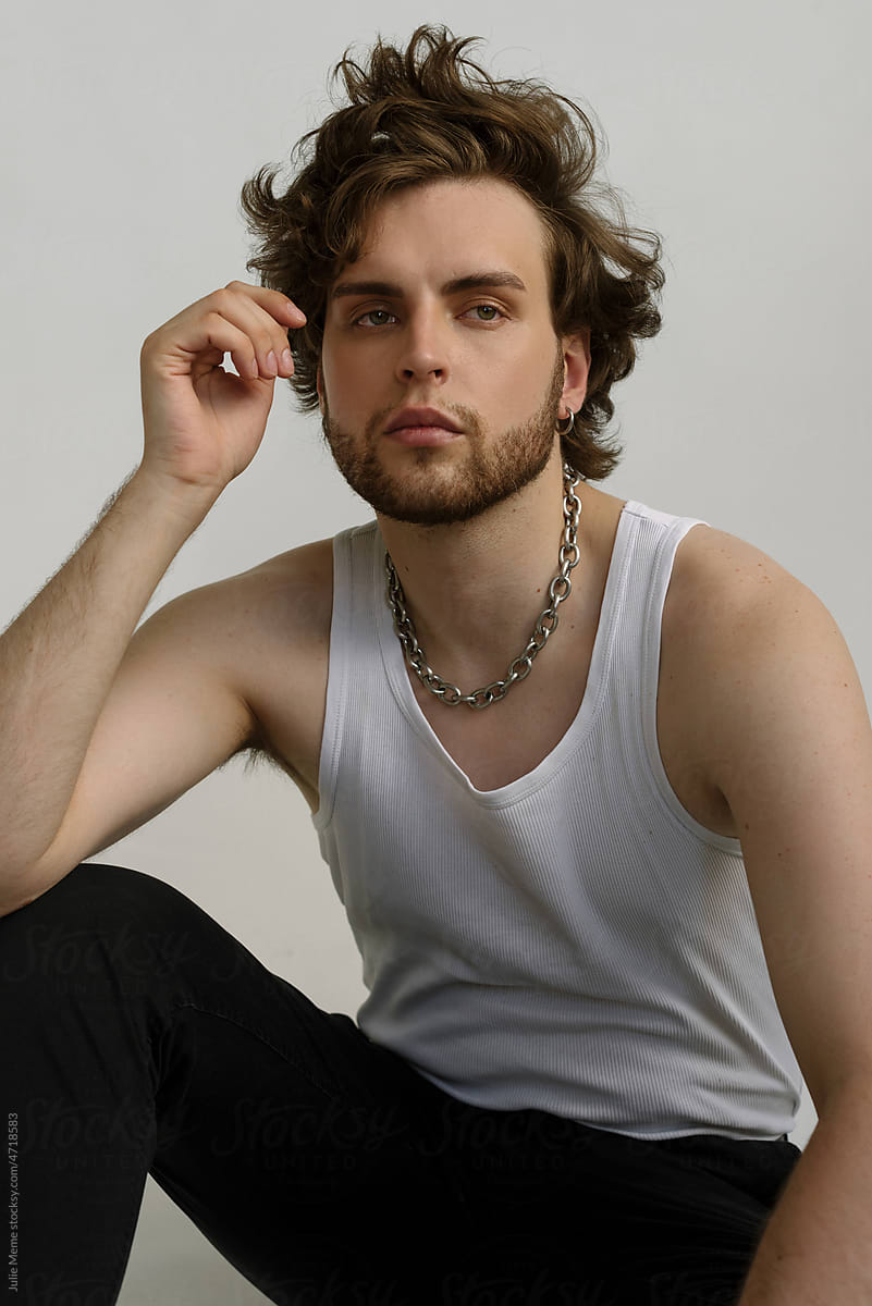 Handsome bearded guy with messy hair in a white shirt and chain