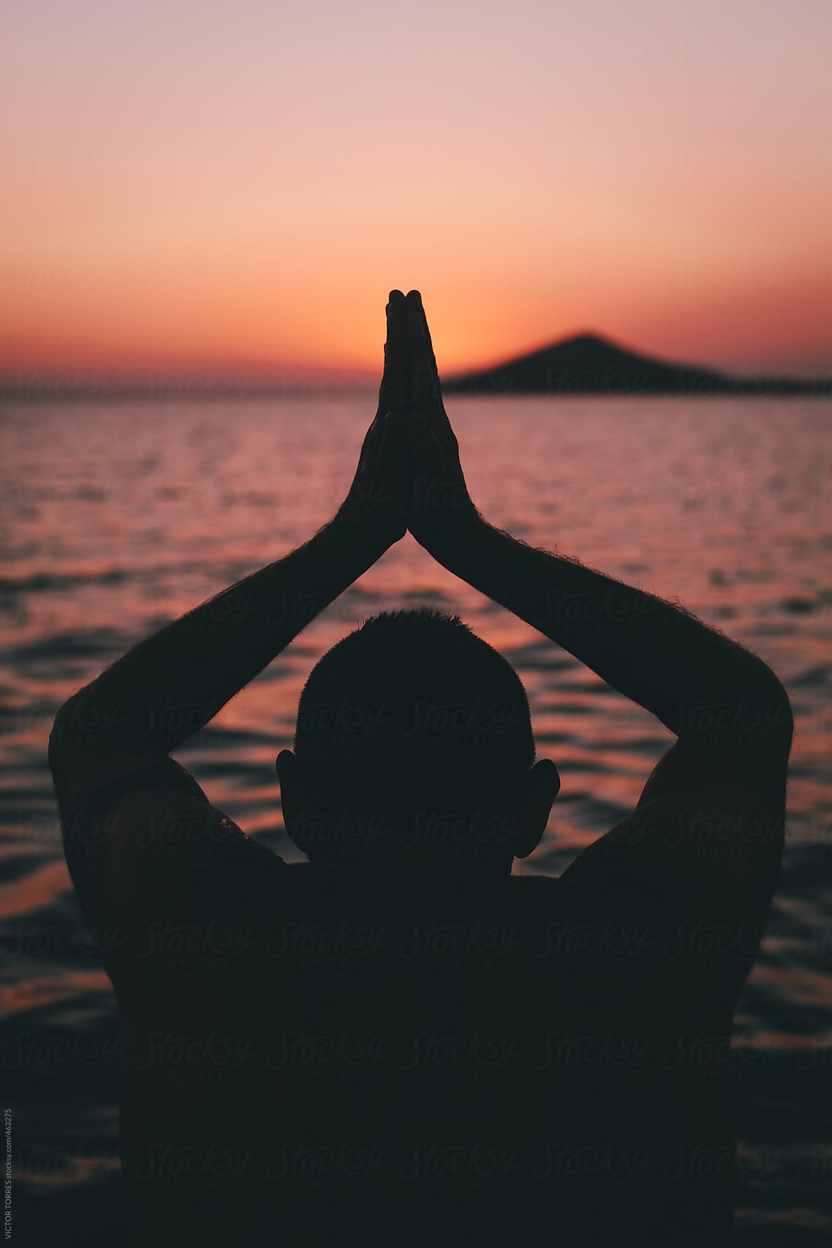 Man Practices Sun Salutation Yoga on the Beach at Sunset