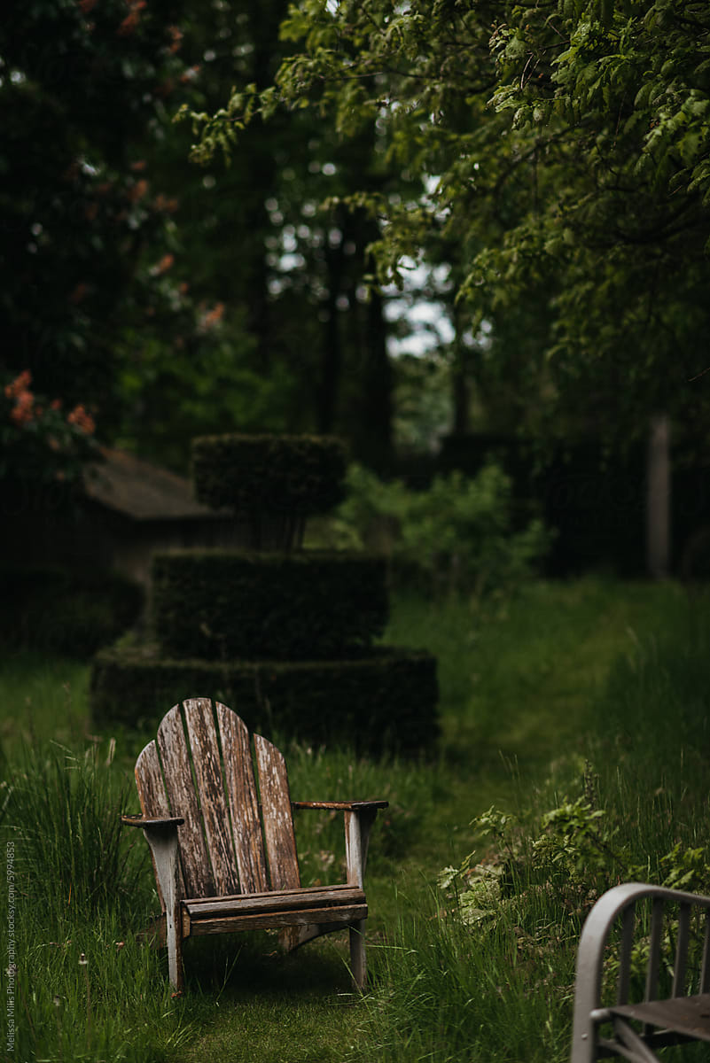 Wooden garden chairs in garden with overgrown grass