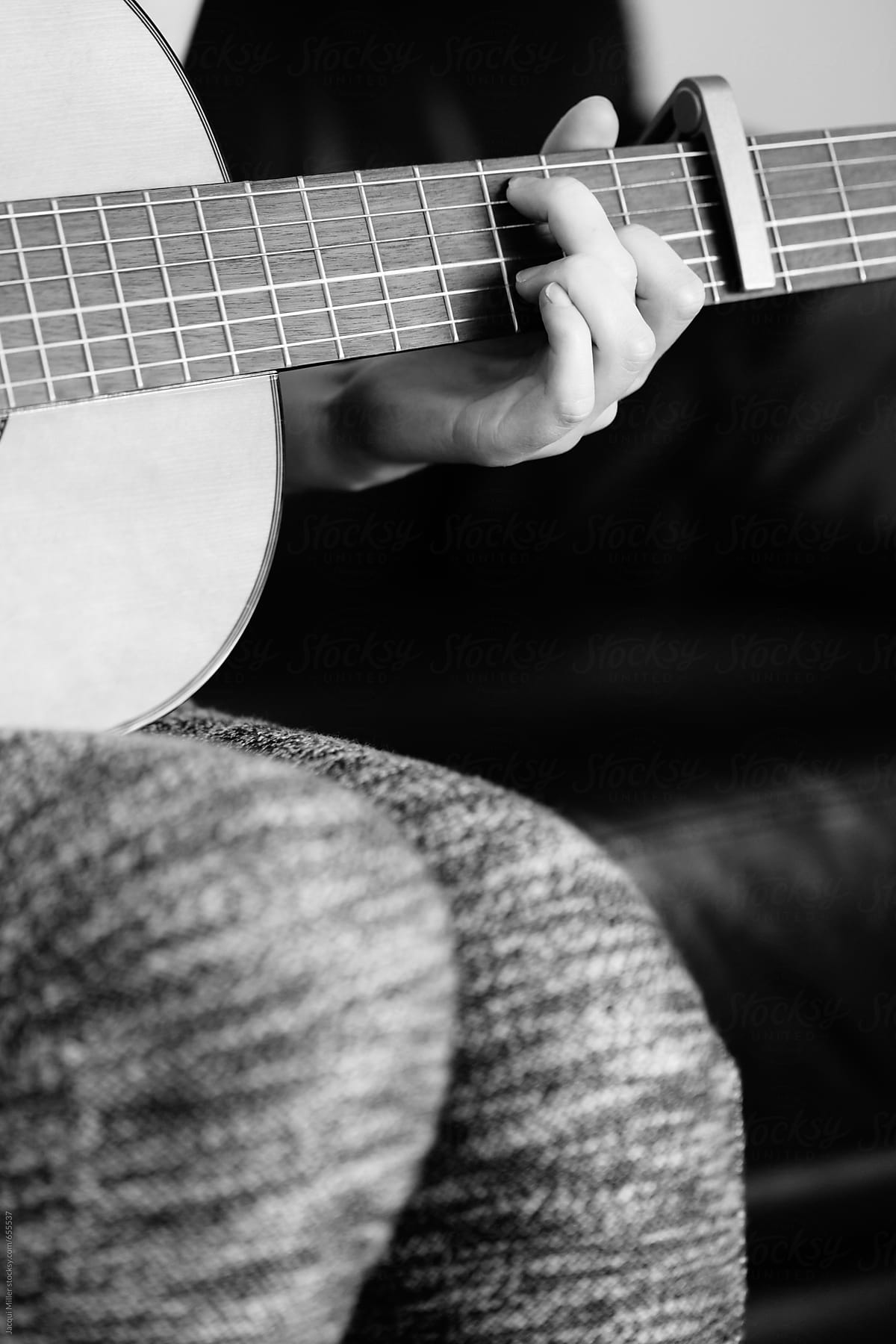 Black and white of girls hand playing a guitar - vertical