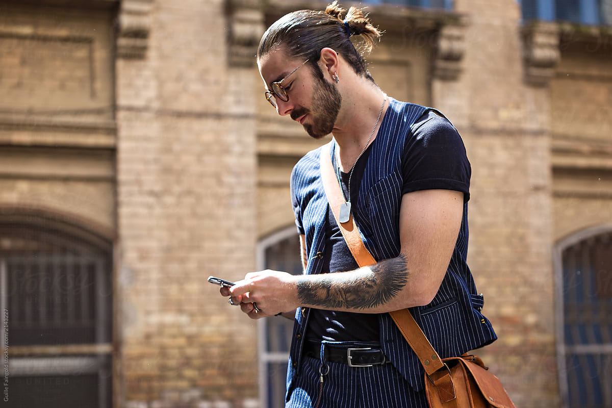 Bearded hipster in glasses using mobile phone.