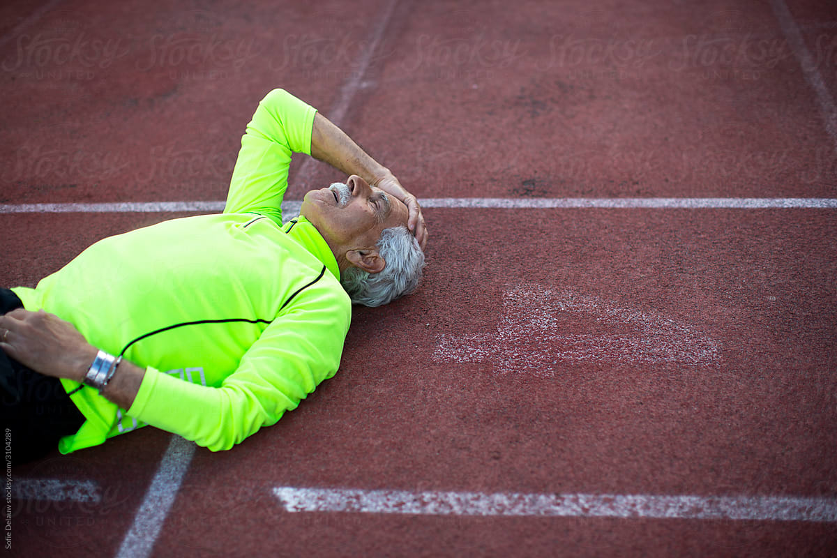 Exhausted aged sportsman lying on track
