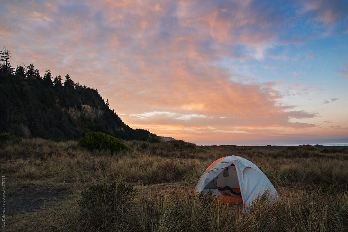 Sunset on the Northern California coast with a tent pitched in the beach grass.