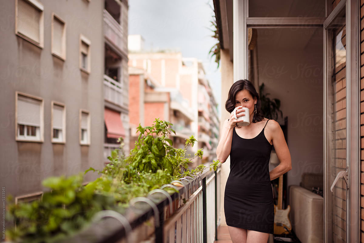 Woman drinking coffee at city balcony