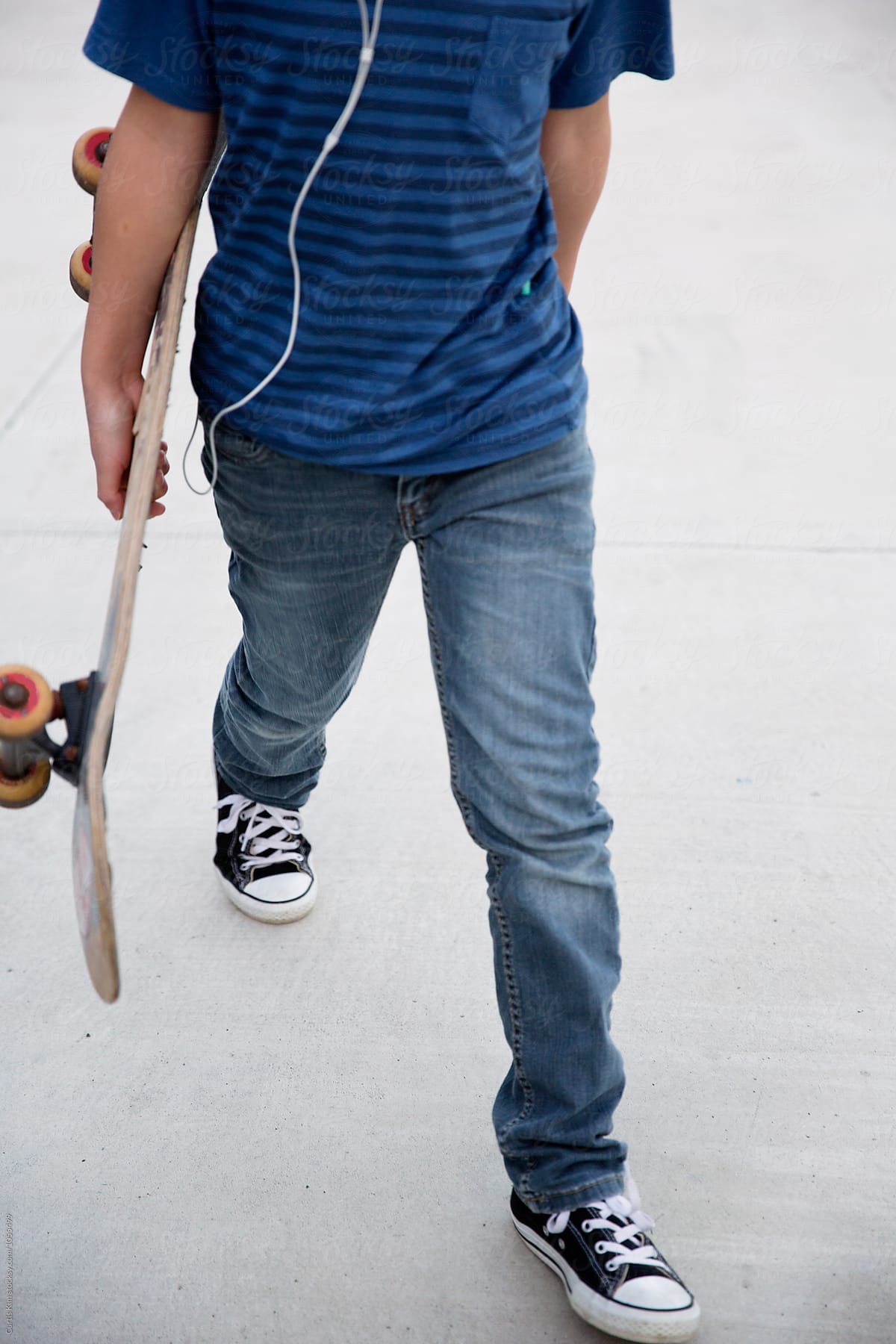 Walking while listening to music and holding his skateboard