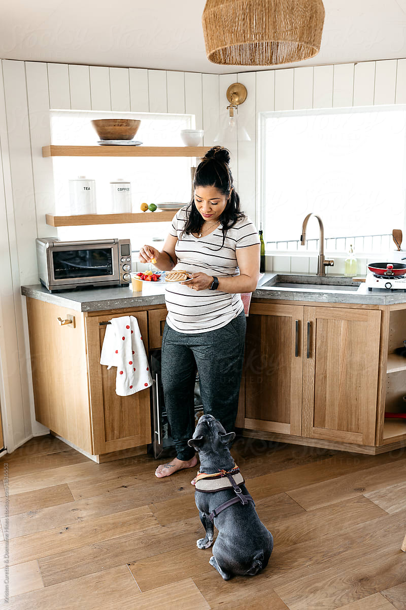 A pregnant woman cooking breakfast a small kitchen