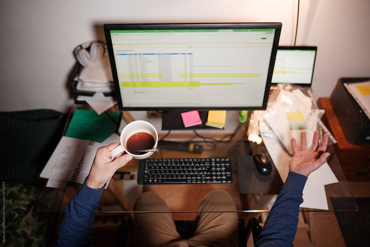 Anonymous holding coffee while working on computer