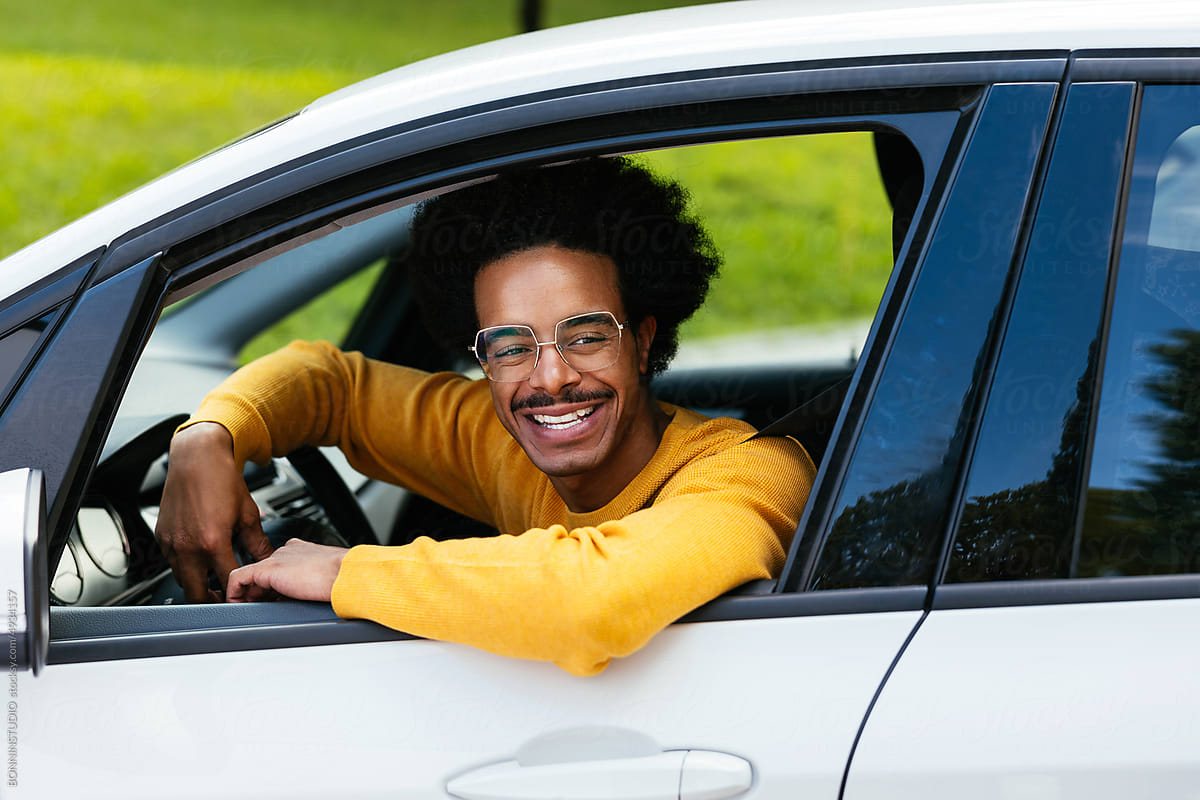 Cheerful mixed race driver peeking from car window