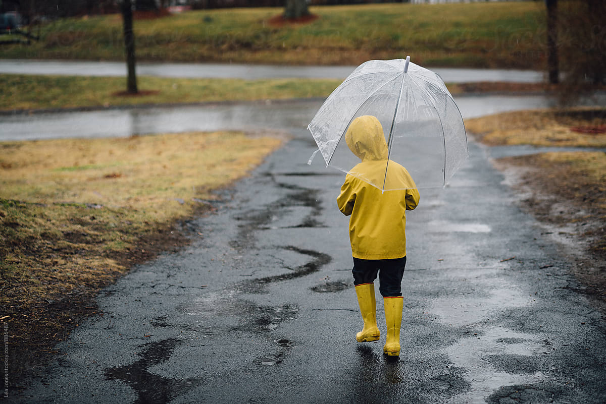 little boy walking with umbrella in the rain