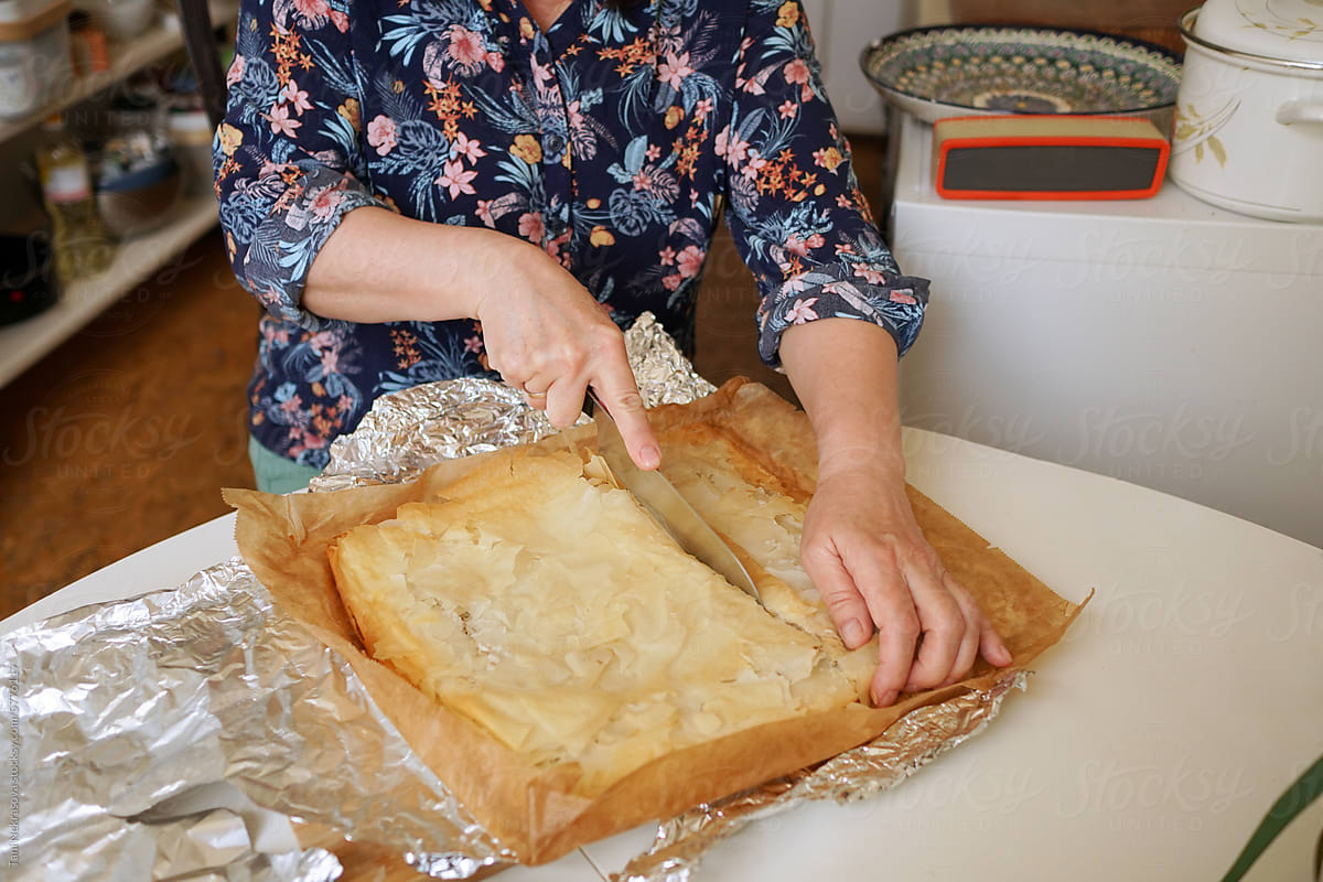 The woman\'s hands cut the cooked pie in a cozy kitchen at home