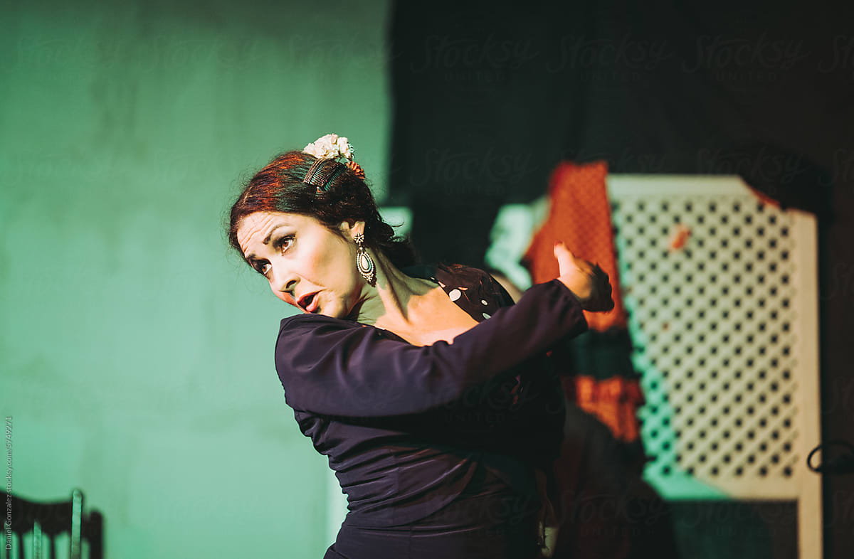 Focused young Spanish female dancing flamenco on stage