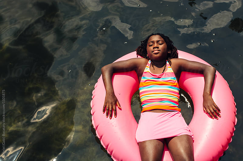 Black girl relaxing on a pink float