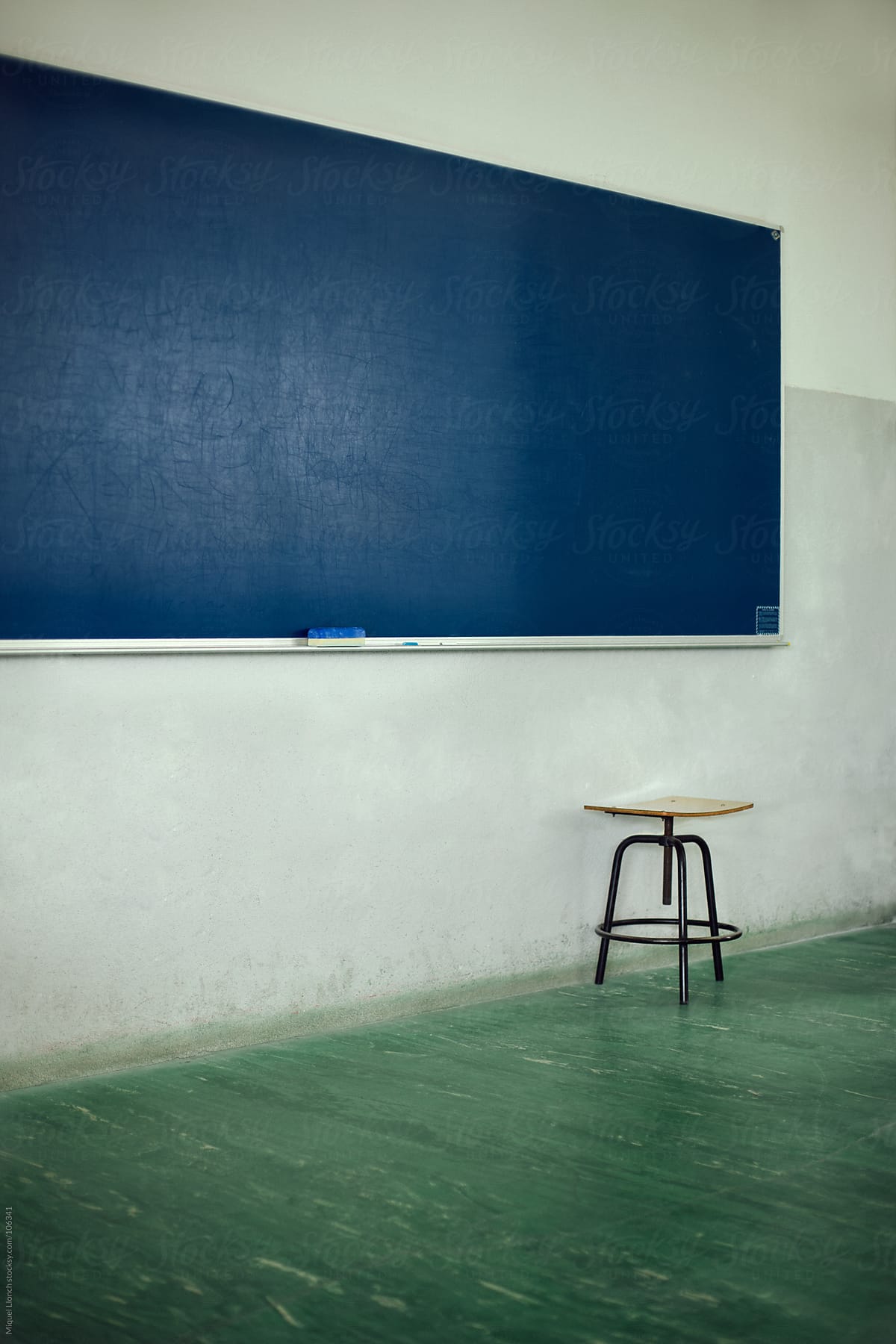 School blue chalkboard in a classroom with a lonely old stool