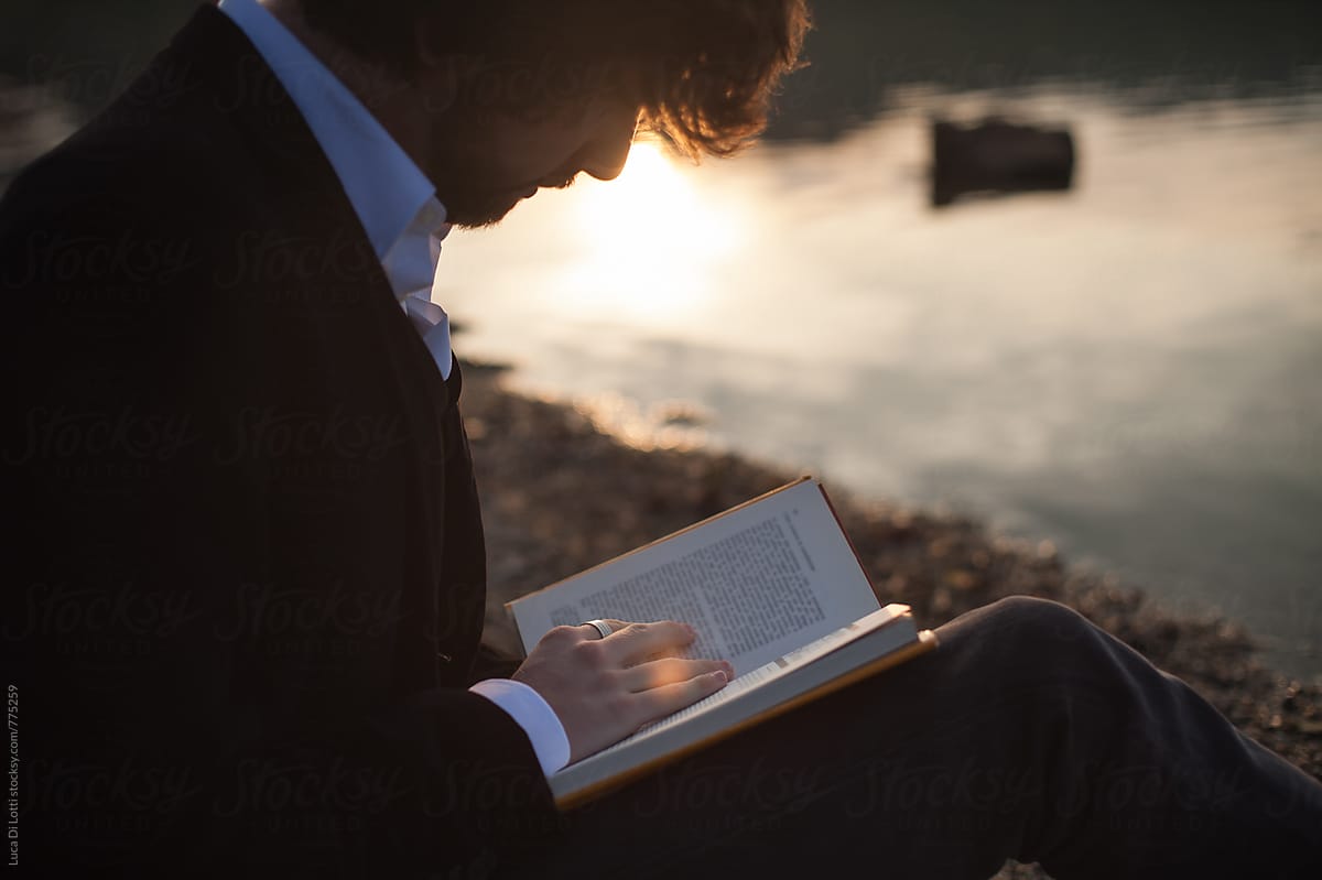 young man reading a book at sunset