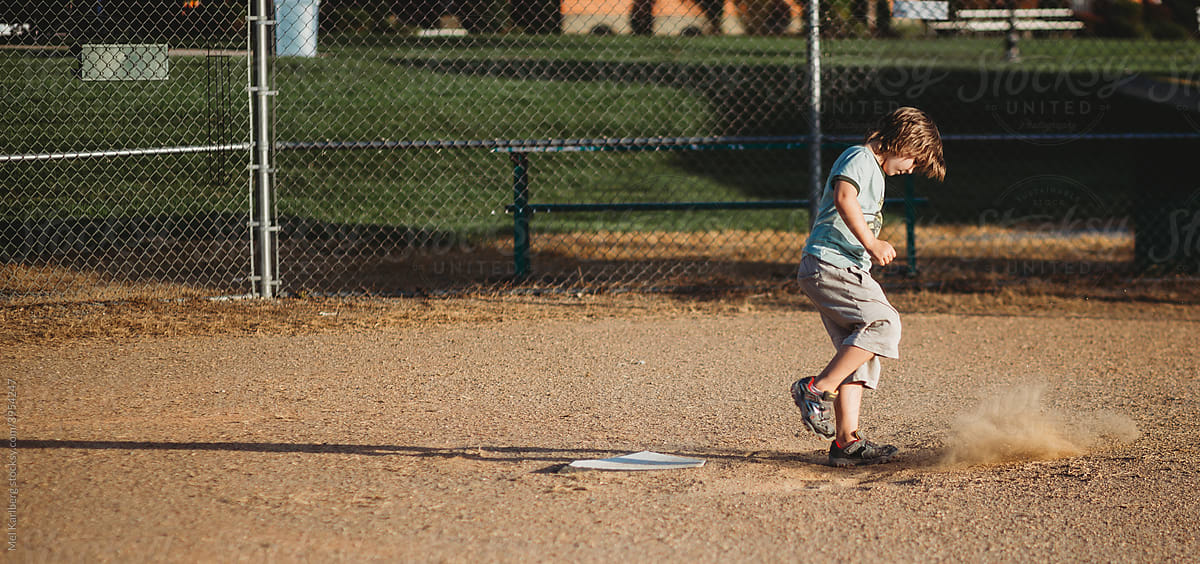 Boy kicking up dust on empty baseball field