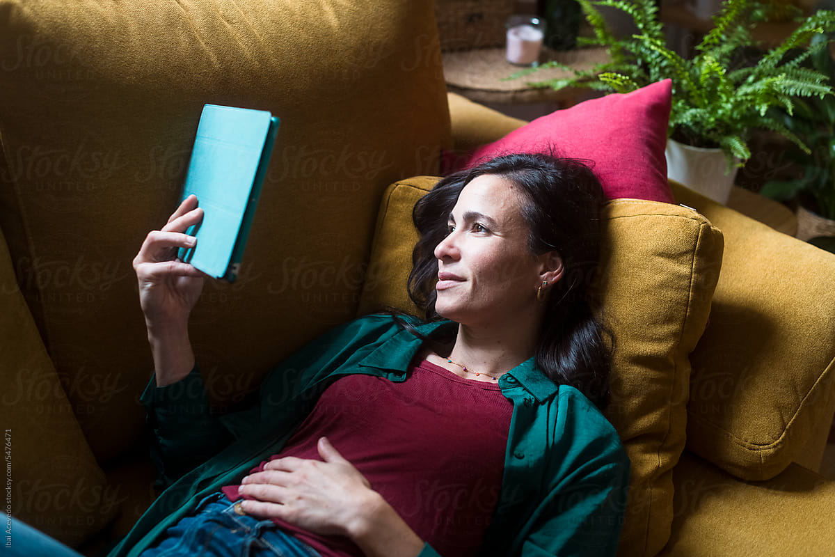 Smiling woman using tablet on cozy couch at home