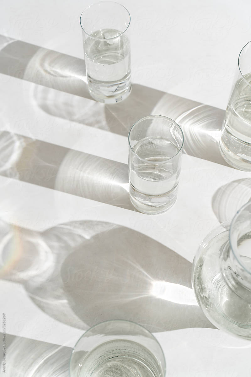 Sunlight falls at glasses of water on light background
